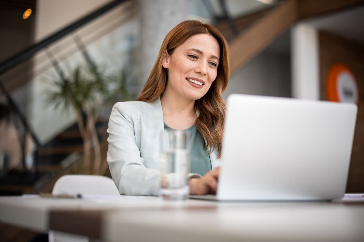 A partner manager smiling while working on a laptop in a modern office