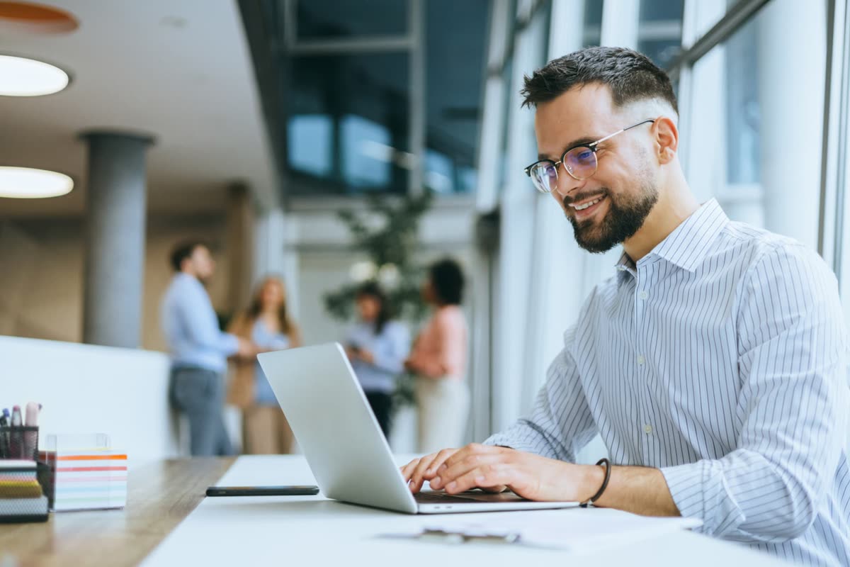 An MSP account manager working on a laptop in a bright open-plan office